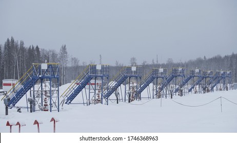 Industrial oil pump equipment working and pumping crude oil for fossil fuel energy with drilling rig in oil field in winter. Equipment for wellhead connection oil well.