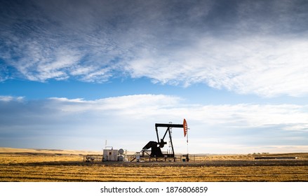 An industrial oil pump jack working on farm land under a morning sky in Rocky View County Alberta Canada. - Powered by Shutterstock