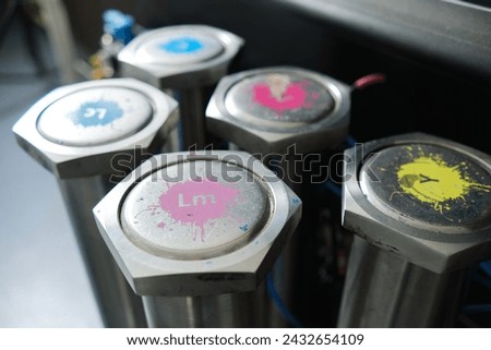 Industrial printing Cyan magenta yellow black and pink colour inkjet and laser jet ink metal cartridges on an industrial printing machine in a print house. Mass bulk printing.