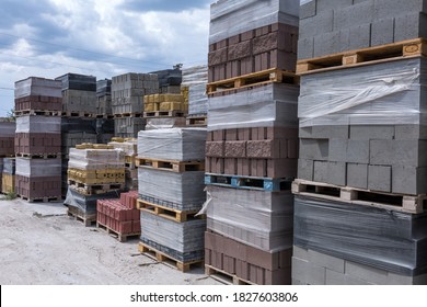 Industrial production of building cement pressed materials. High quality hollow concrete block or cement brick and paving stones. Finished products on pallets packed in film are waiting to be shipped. - Shutterstock ID 1827603806