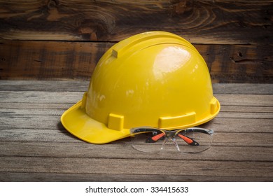 Industrial Protective Workwear. Includes Hard Hat And Safety Glasses On Wooden