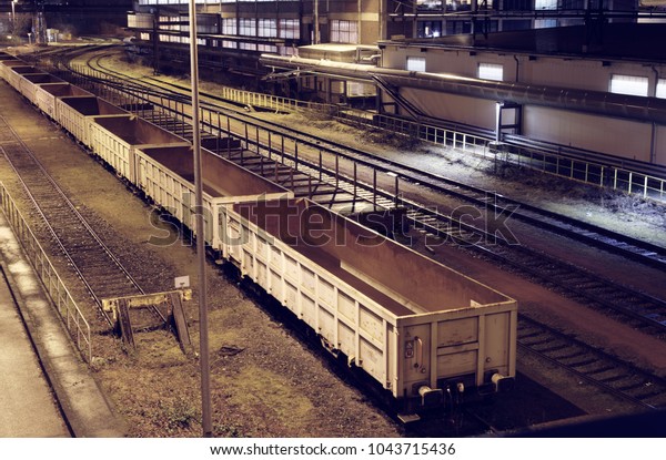 Industrial rail yard\
shunting station at night with many lights and wagons on a siding\
in an industrial\
plant