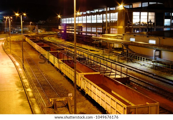 Industrial rail yard\
shunting station at night with many lights and wagons on a siding\
in an industrial\
plant