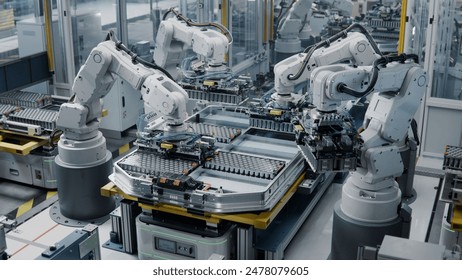 Industrial Robot Arms Assemble Lithium-Ion EV Battery Pack. Row of White Robotic Arms at Automated Production Line at Bright Modern Factory. Electric Car Manufacturing Inside Automotive Smart Factory