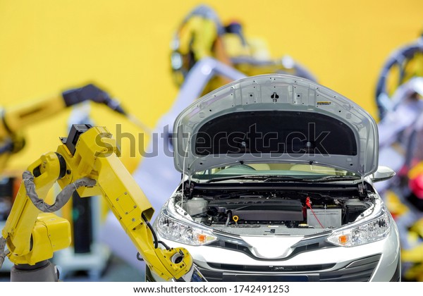 Industrial robotic working with automobile on\
blurred smart car factory background, robot work instead of human,\
industry 4.0 and AI\
concept