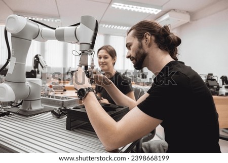 Industrial Robotics program university students learning education mechanical assembly with Robot Universal Training Platform robot arm simulation model in engineering lab classroom.