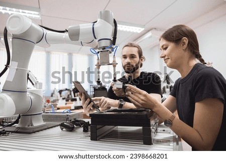 Industrial Robotics program university students learning education mechanical assembly with Robot Universal Training Platform robot arm simulation model in engineering lab classroom.