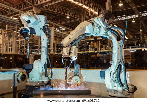 Industrial robots are welding in automotive\
industrial factory\
