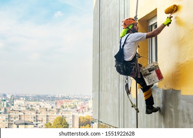Industrial Rope Access Worker Hanging From The Building While Painting The Exterior Facade Wall. Industrial Alpinism Concept Image