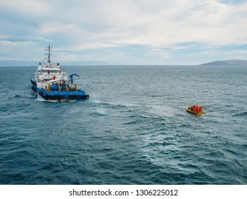 Industrial Seismic Ship Vessel And Orange Boat In Sea. Industrial Offshore Working And Searching For Oil In Ocean