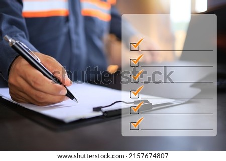 An industrial or shipping inspector auditor supervisor in a reflective jacket is writing a pen on a clipboard to check the inventory of tasks that need to be done and has a checklist icon on the right