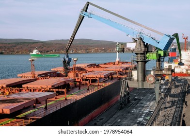 Industrial ships at the mooring wall in the seaport in the Kola Bay.
  The holds of the ship are filled with bulk cargo of mineral origin