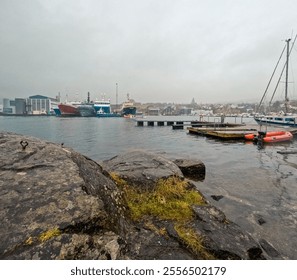 Industrial shipyard on the North Atlantic Ocean in Tórshavn, the Capital City of the Faroe Islands. Views across the bay to buildings and colorful boats in the marina. - Powered by Shutterstock