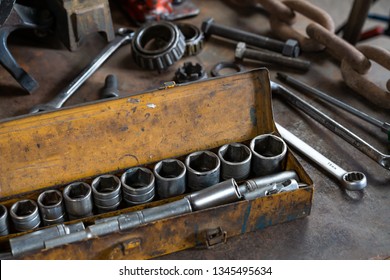 Industrial Socket Set Inside A Yellow Toolbox On A Work Bench - Ratchet Socket Kit Next To Various Hand Tools And Replacement Parts