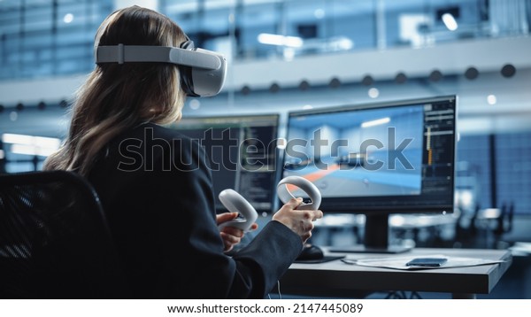 Industrial Software Developer Writing Code\
and Testing Automotive Manufacturing Interface. Engineer Editing\
Electric Motor and Car Chassis while Wearing Virtual Reality\
Headset and Using\
Controllers.