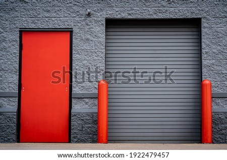 Industrial stone building with red door and roll up bay door