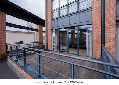 Industrial style apartment building with stylish terrace, big windows and designed walls with exposed red brick