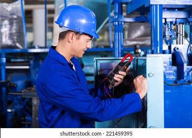industrial technician examining control box with digital insulation tester