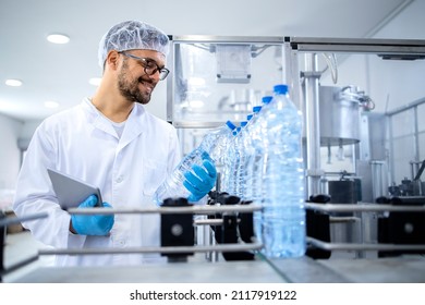 Industrial technologist holding tablet computer and checking production of bottled water in bottling factory on automated machine. - Powered by Shutterstock