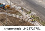 Industrial truck loader excavator moving ground and loading into a dumper truck timelapse on road construction site. Aerial view of reconstruction of tram tracks with rails installation