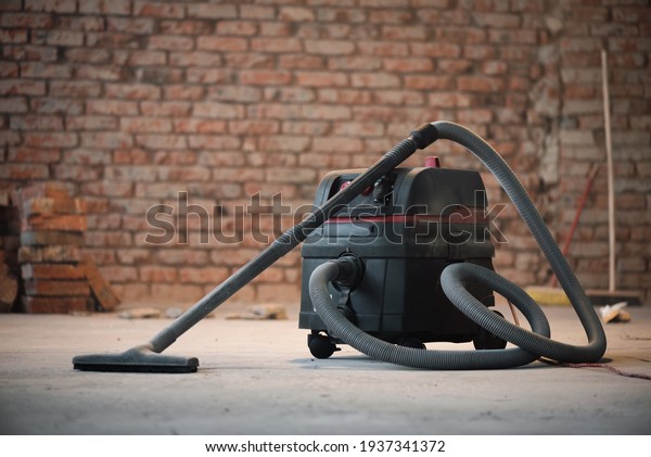 Industrial vacuum cleaner on the dusty floor of\
construction site.