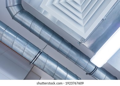 Industrial ventilation system and the lamp on the ceiling. Ceiling of the working room. Bottom view of the metal pipes of the ventilation hood. Indoor air purification system.