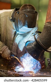 Industrial Welder Worker Welding Steel At Factory Workshop With Welding Fume And Dust Extractor And Flying Sparks