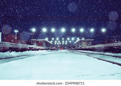 Industrial winter night landscape - illuminated railway station by winter night under light snowfall, concept of winter night travels - Powered by Shutterstock