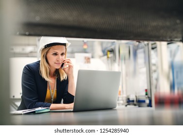 Industrial Woman Engineer In A Factory Using Laptop And Smartphone.