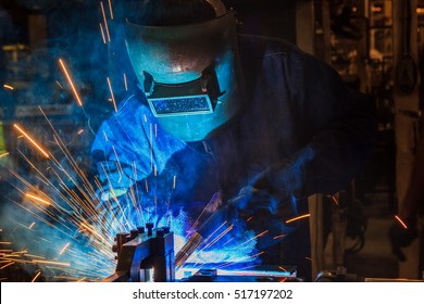 Industrial Worker At Assembly Line In Car Factory Is Welding Automotive Part, Close Up

