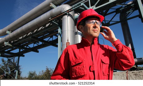 Industrial Worker With Cell Phone / Worker with personal protective equipment using cell phone in factory premises.