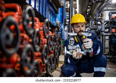 Industrial worker changing the high pressure pipe valve in heating plant.