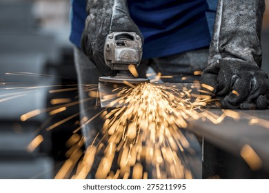 Industrial worker cutting metal with many sharp sparks