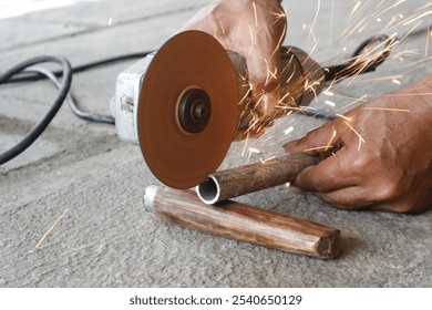 Industrial Worker Cutting Metal Pipe with Grindstone Abrasive Disc Cutter Machine Without Gloves, Illustrating Risky Work Practices and Lack of Safety Precaution. Iron  Spark Particles from Grindstone - Powered by Shutterstock