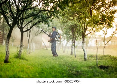 Industrial Worker And Farmer Using Spraying Machine For Pesticides And Insecticide