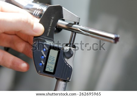 Industrial worker measure detail with digital caliper micrometer at factory workshop