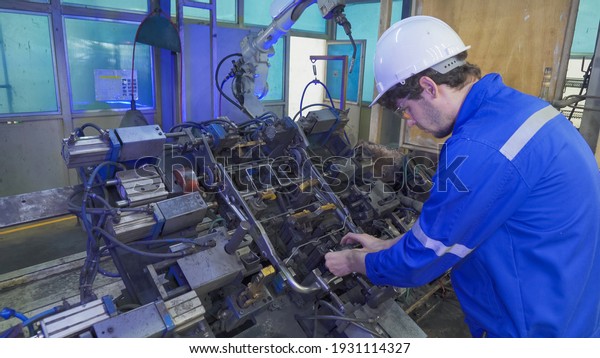 Industrial worker on quality control using steel\
measuring tape measure length a part of an operation machine at\
factory site with the smart robot welding hand system automated\
manufacturing\
machine.