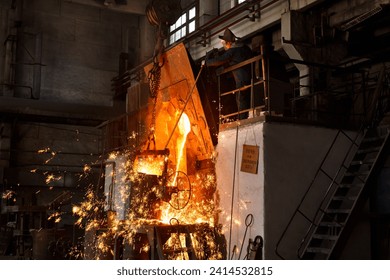 Industrial worker oversees molten metal pouring in foundry. Steelworker in protective gear at metal manufacture. Heavy industry scene with fiery sparks, furnace heat in steel mill. - Powered by Shutterstock