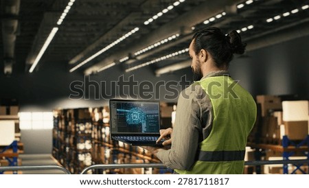 Industrial worker using AI-powered software with machine learning on laptop, artificial intelligence and neural networks supporting e-commerce operations for large business in fulfillment center.