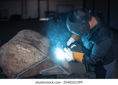 Industrial worker wearing protective gear, welding a piece of metal in a workshop, creating bright sparks - Powered by Shutterstock