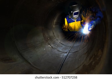 Industrial Worker Welding Metal And Many Sharp Sparks Inside Piping Construction With Confined Space .