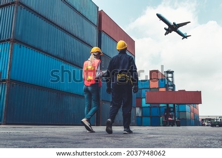 Industrial worker works with co-worker at overseas shipping container port . Logistics supply chain management and international goods export concept .