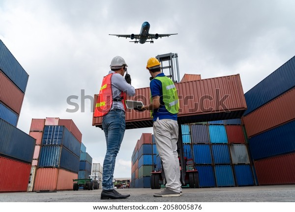 Industrial worker works with co-worker at\
overseas shipping container port . Logistics supply chain\
management and international goods export concept\
.