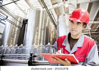 Industrial worker writes on a paper conditions in a filling line production of drinking water.Shallow doff