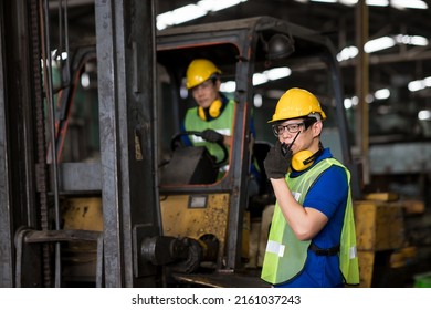 Industrial Worker In Yellow Hard Hat Talking On Walkie-talkie For Forklift In Warehouse, Workers Freight Transportation And Distribution Warehouse.