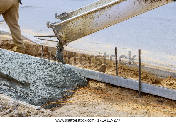 Industrial workers pouring fresh concrete on\
reinforced cement\
sidewalk