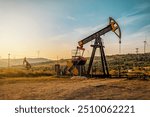 Industrial working oil pump on crude oil field at sunset