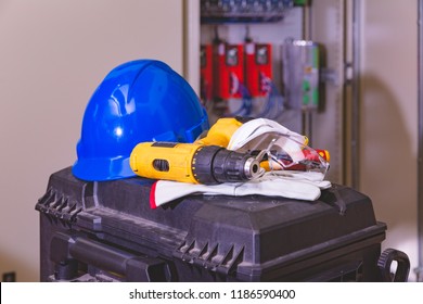 Industrial Working With Safety Concept, PPE  (Personal Protective Equipment) For Professional Worker Or Electrician. Electric Drill , Blue Hardhat, Glove And Transparency Glasses Put On Tool Box.