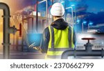 Industrialist has back to camera. Man looks at factory structures. Guy with laptop in factory. Industrialist of territory of evening plant. Man in reflective vest. Specialist of modern plant