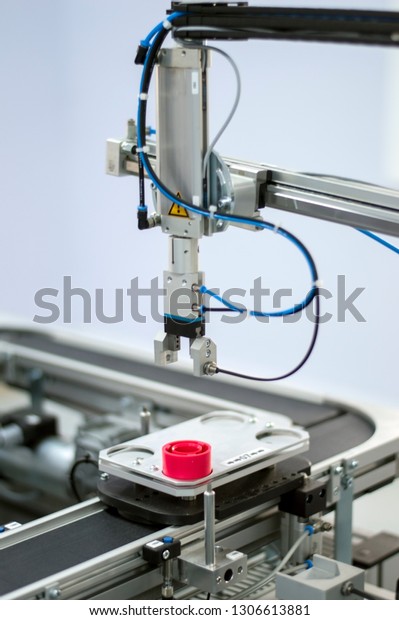 Industry 4.0 concept; artificial intelligence in\
manufacturing. Focus on the gripper. Gripper picks up product from\
automated car on the automated production line in a smart factory.\
Selective focus.